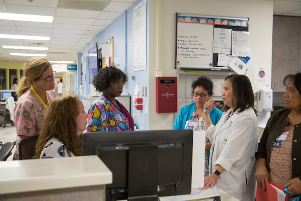 a physician and nurses in discussion at a nurses station