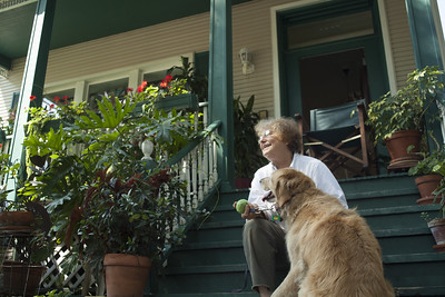 older woman with a dog, sitting on house porch